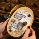 Heart-shaped wooden box with decorative elements held by a person against a wooden background.