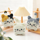 Three knitted cat toys on a wooden surface with a lamp in the background.