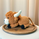 Crocheted toy cow on a wooden tray with a neutral background