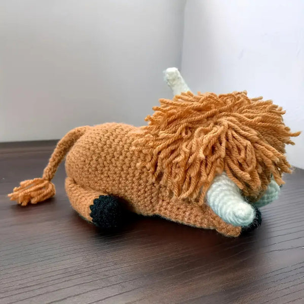 Knitted lion toy on a wooden surface with a white background