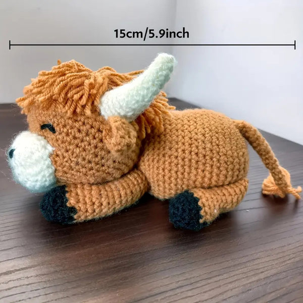 Crocheted bull toy with measurement label on a wooden surface
