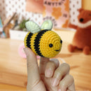 Hand holding a small crochet bee toy with a blurred background