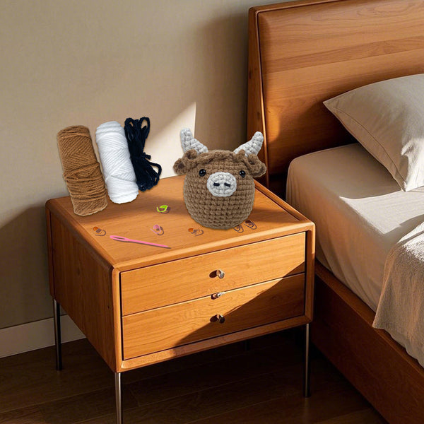 Wooden nightstand with crochet deer and yarn, next to a bed.