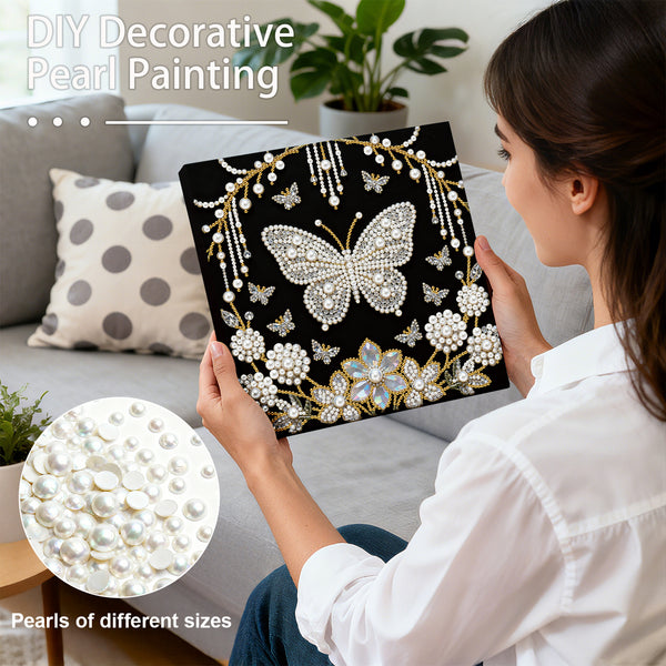 Woman holding a decorative pearl painting with a butterfly design, surrounded by pearls.