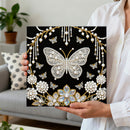 Person holding a decorative panel with a butterfly design and pearls.