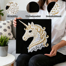 Person holding a decorative unicorn artwork with pearl embellishments, surrounded by a living room setting.
