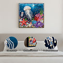 Decorative wall art of an underwater scene with a jellyfish, starfish, and coral on a plain wall.