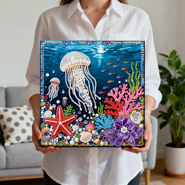 Person holding a completed diamond painting of an underwater scene with jellyfish, starfish, and coral.