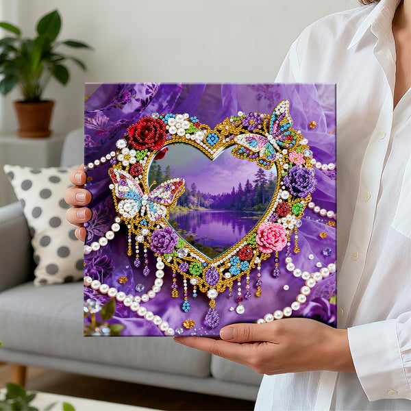 Person holding a diamond painting with a heart design and nature scene, set against a purple background.