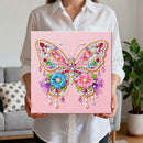 Person holding a pink canvas with a colorful butterfly design made of beads and pearls.