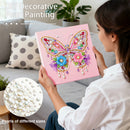 Woman holding a DIY decorative pearl painting of a butterfly with colorful flowers, sitting on a couch.
