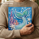 Person holding a DIY decorative pearl painting of a mermaid tail with underwater elements.