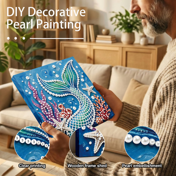 Person holding a DIY decorative pearl painting with mermaid design in a living room.