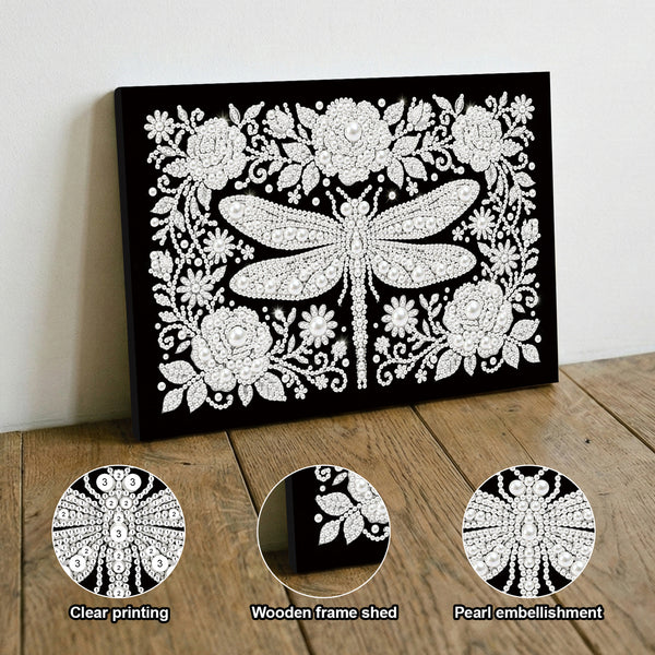 Decorative wall art with a dragonfly design on a black background, displayed on a wooden surface.