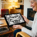 Woman holding a decorative pearl painting of a dragonfly and flowers in a cozy living room.