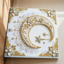 Decorative wall art with a moon, stars, and pearls on a marble background