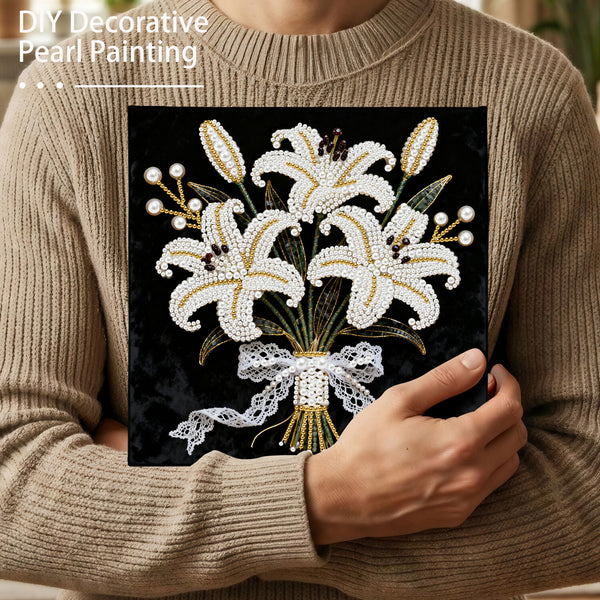 Person holding a completed pearl painting of flowers, wearing a beige sweater.