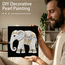 Man holding a completed pearl painting of an elephant in a home setting
