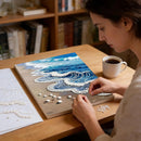 Woman working on a mosaic art project with a cup of coffee on a wooden table.