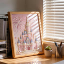 Framed artwork of a castle with fireworks on a desk with a plant and pen holder.