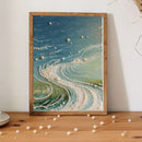 Framed artwork with a wave design and scattered pearls on a wooden surface.