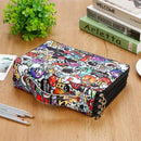 A zippered fabric pouch with a colorful cartoon graffiti print, displayed on a wooden tabletop with books, pencils, and a plant.