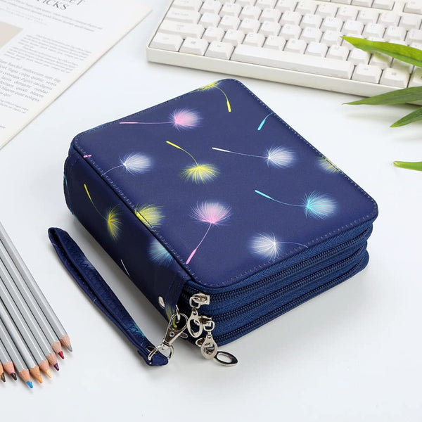 A navy blue zippered wallet or organizer case with a dandelion print, shown on a white desk with a keyboard, pencils, and a plant in the background.