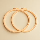 Two wooden embroidery hoops on a beige background