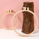 Two wooden embroidery hoops on a pink background with a wooden block.