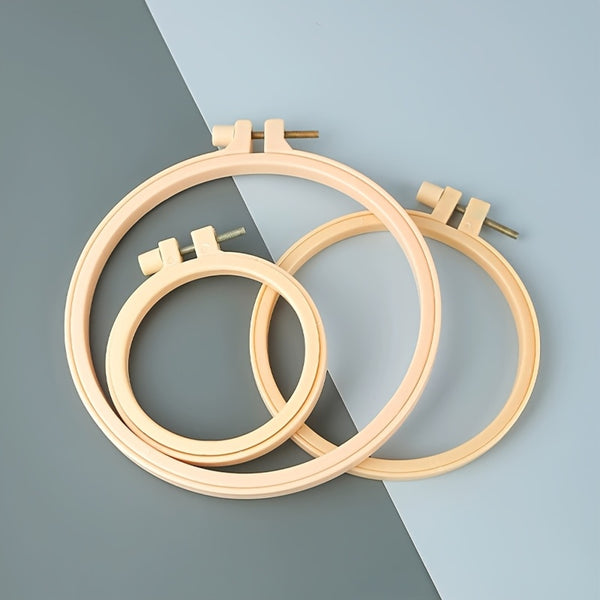 Three wooden embroidery hoops on a two-tone gray and blue background