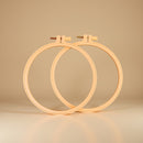 Two wooden embroidery hoops on a beige background