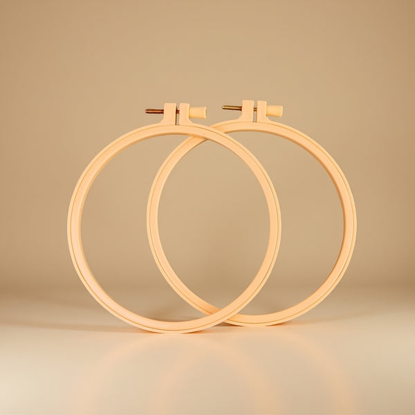 Two wooden embroidery hoops on a beige background