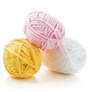 Three balls of yarn in pink, yellow, and white on a white background