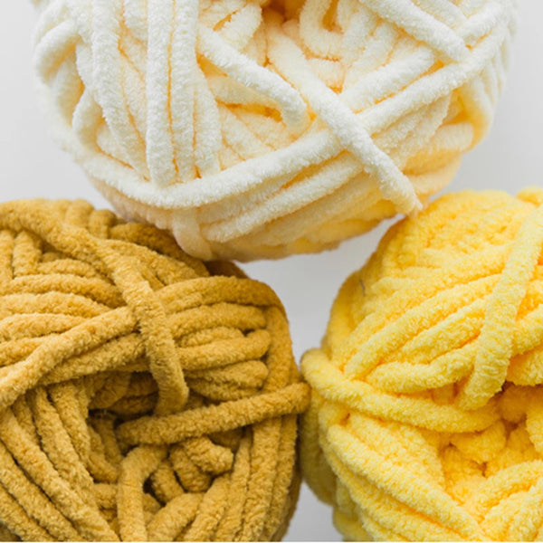 Three balls of yarn in white, yellow, and mustard on a light background