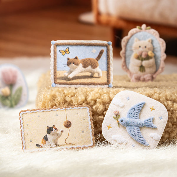 Collection of embroidered items featuring cats and birds on a textured surface.