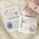 Two decorative cards with illustrations and text on a textured surface with pillows.