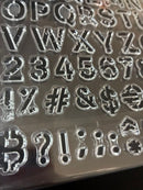 Transparent plastic stamps with letters, numbers, and symbols on a reflective surface