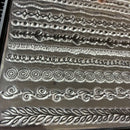 Collection of metal embossing folders with various decorative patterns on a metallic surface.