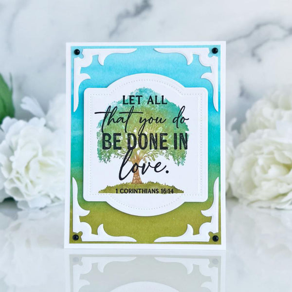 Card with 'Let all that you do be done in love' quote and tree design on a marble background with flowers.