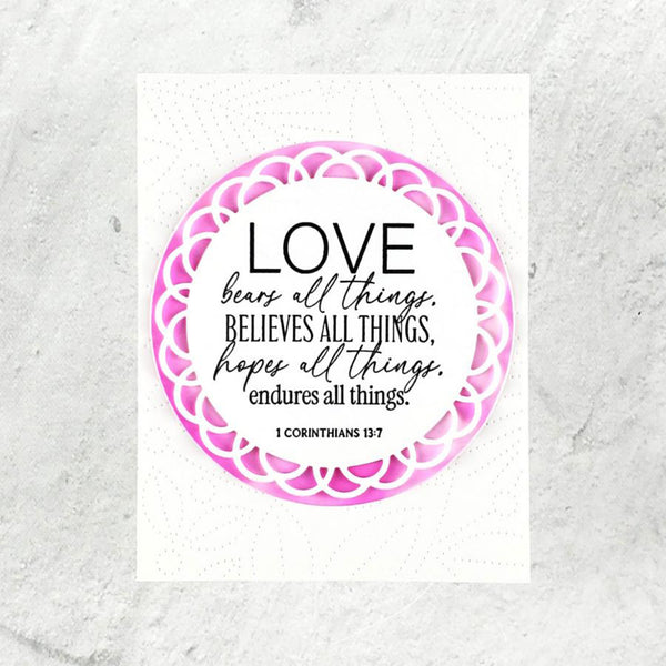 Circular design with motivational quote 'Love bears all things, believes all things, hopes all things, endures all things.' from 1 Corinthians 13:7, framed by a pink and purple mandala on a textured white background.