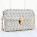 A chunky white crocheted shoulder bag with a gold-tone clasp and chain strap, set against a soft white background.