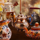 Collection of ornate teapots with floral designs on a wooden surface.