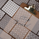 Collection of patterned paper sheets with a gold clip on a checkered background