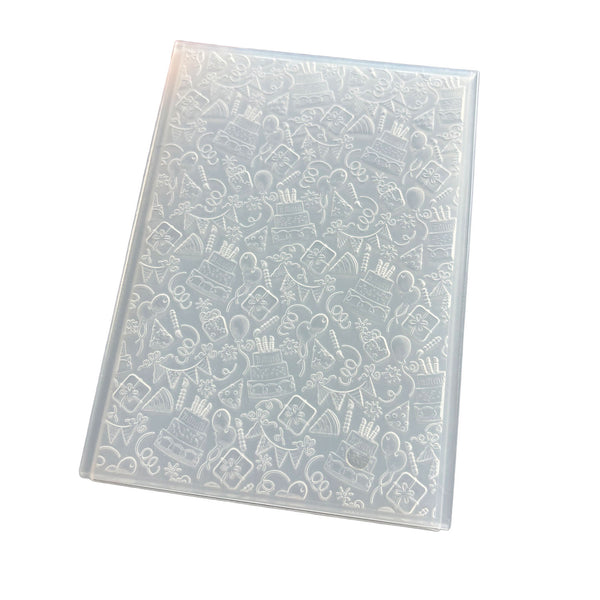 A clear plastic sheet containing embossed white cake-themed illustrations, shown at an angle on a plain white background.