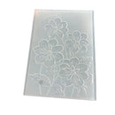 A rectangular translucent plastic mold or stamp featuring an embossed floral pattern of four large flowers and leaves, shown on a plain white background.