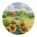 Round needlepoint canvas with sunflowers and a cottage in the background