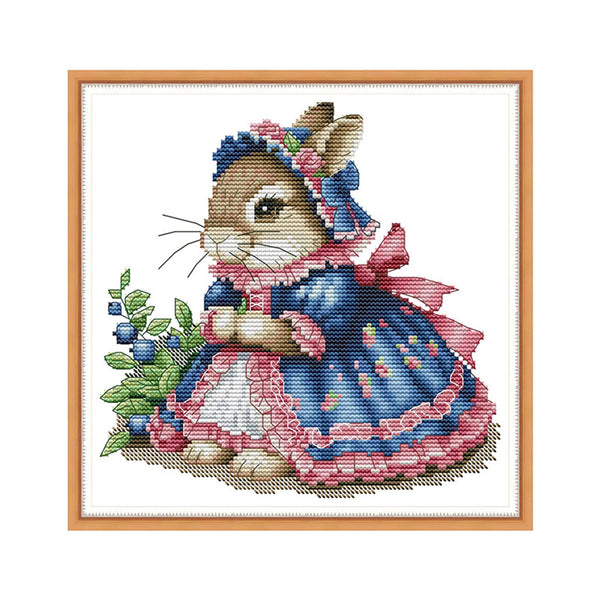 Cross-stitched design of a rabbit in a blue dress with a pink bonnet on a white background.