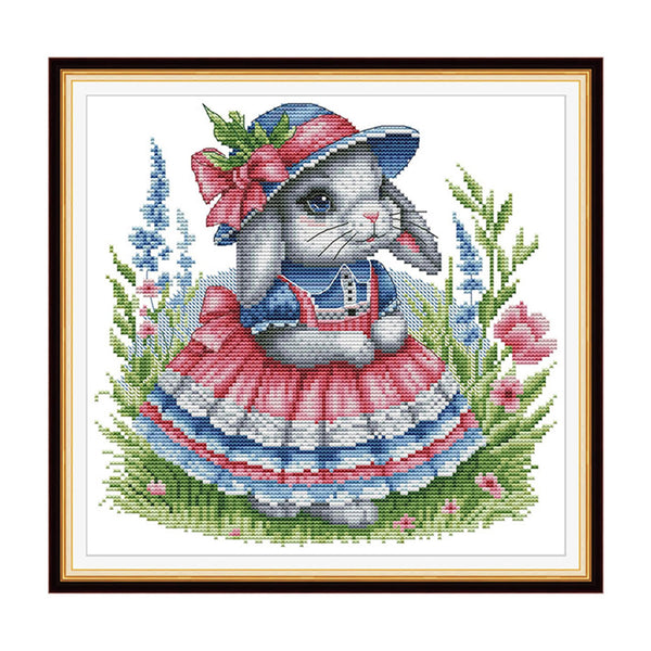 Cross-stitched design of a rabbit in a dress and hat with flowers and grass.