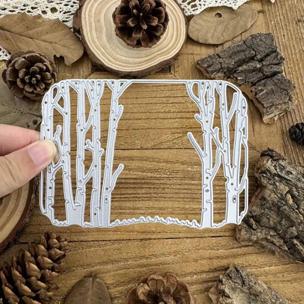 Metal die cut with tree design held over a wooden surface with natural elements.