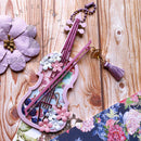 Decorative keychain shaped like a violin with floral elements on a wooden surface.